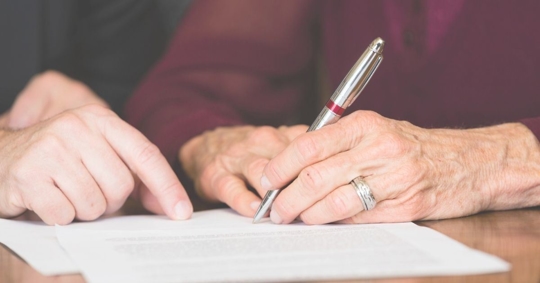 older person signing a document